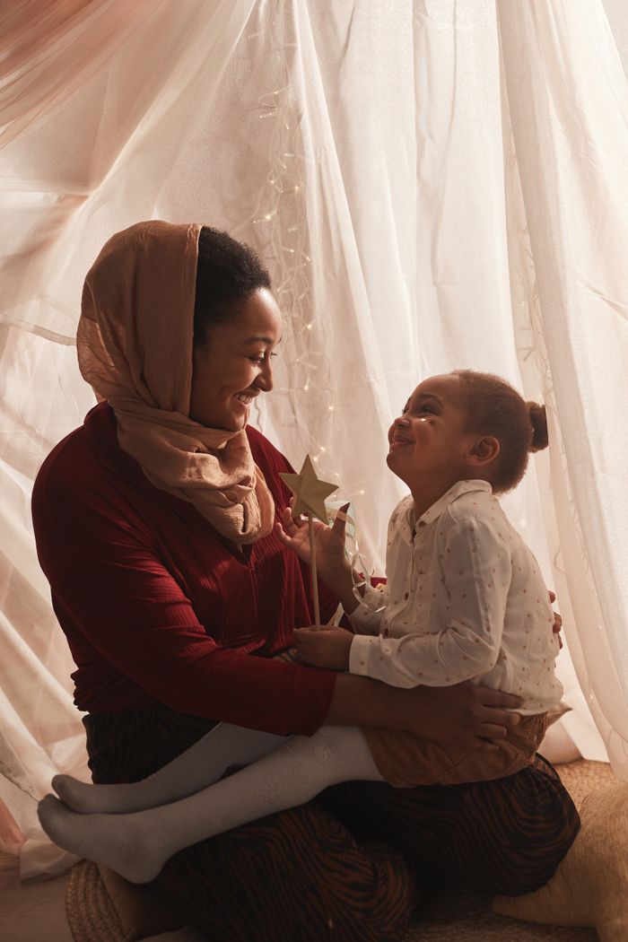 A loving mother and her daughter enjoy quality time together indoors with soft lighting.
